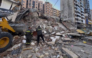 Civil defence workers check a destroyed building that was hit by an Israeli airstrike in Dahiyeh, 24 March